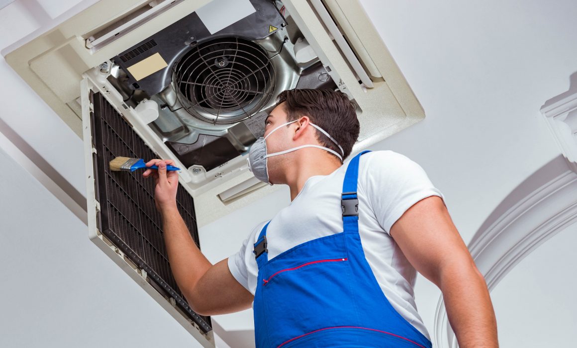 The worker repairing ceiling air conditioning unit for heater
